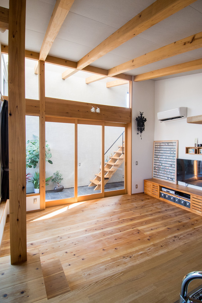 Mittelgroßes, Offenes Modernes Wohnzimmer ohne Kamin mit weißer Wandfarbe, braunem Holzboden, TV-Wand und braunem Boden in Sonstige