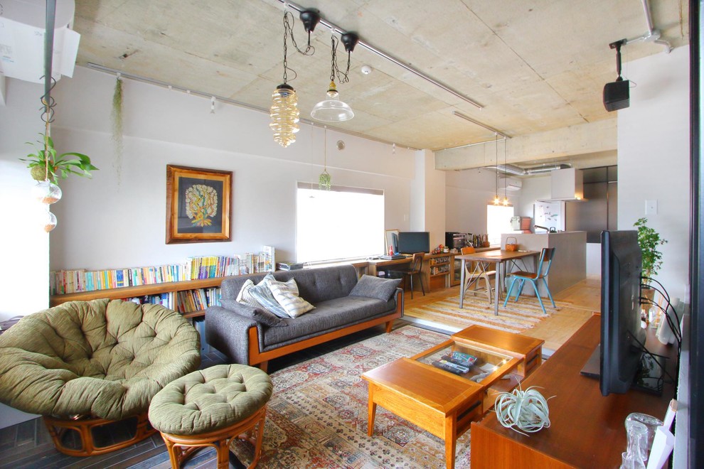 Offenes Industrial Wohnzimmer mit weißer Wandfarbe, hellem Holzboden, freistehendem TV und braunem Boden in Tokio