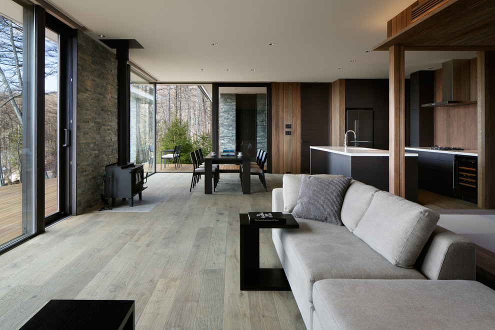 Foto di un soggiorno contemporaneo aperto con pareti marroni, pavimento in legno verniciato, stufa a legna e pavimento grigio