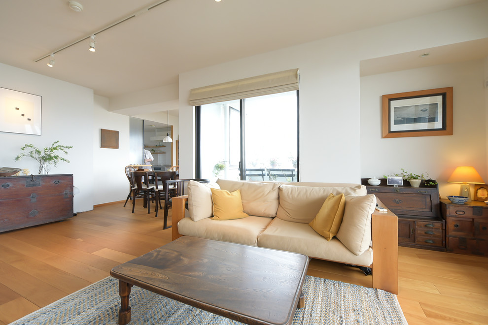 На фото: открытая гостиная комната в современном стиле с белыми стенами, светлым паркетным полом и коричневым полом с