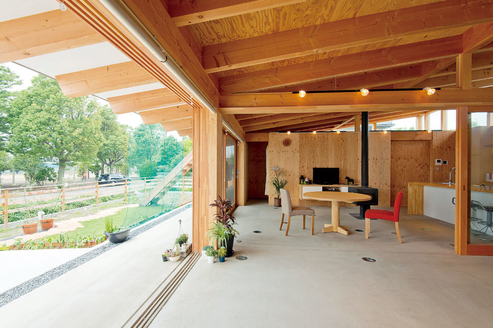 На фото: маленькая гостиная комната в восточном стиле с бетонным полом, печью-буржуйкой и фасадом камина из дерева для на участке и в саду