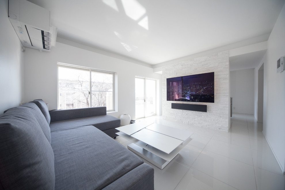 Idée de décoration pour un salon design avec un mur blanc, un téléviseur fixé au mur et un sol blanc.