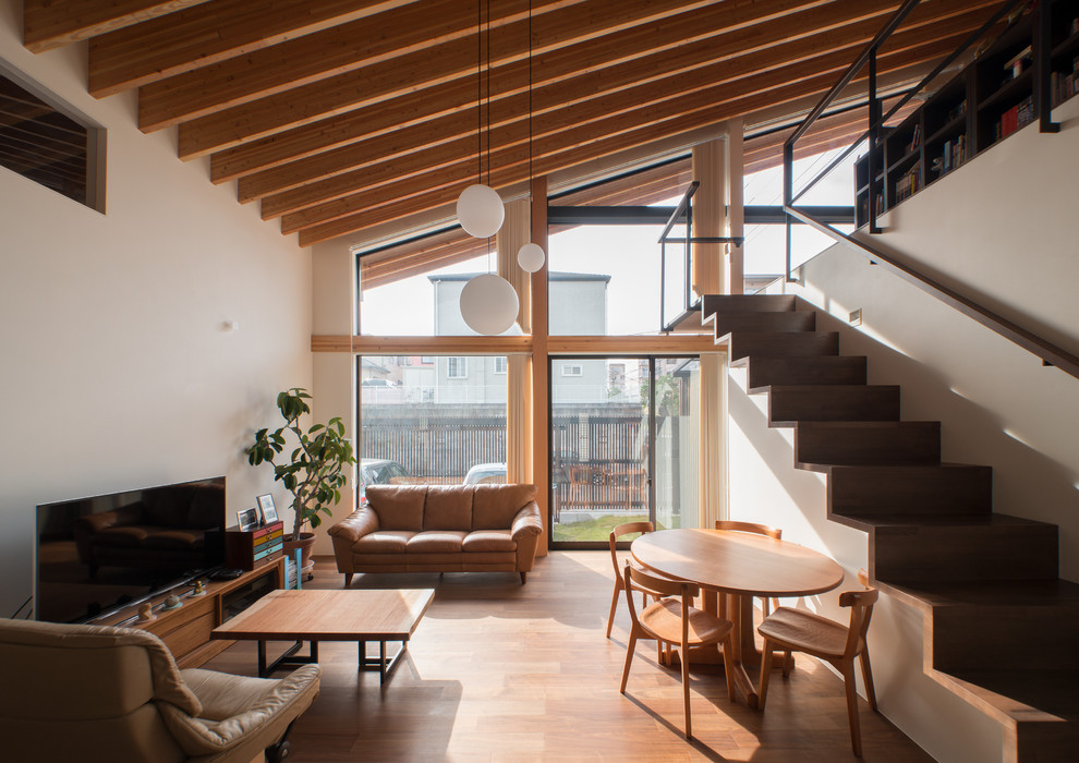 Aménagement d'un salon asiatique ouvert avec un mur blanc, un sol en bois brun, un téléviseur indépendant et un sol marron.