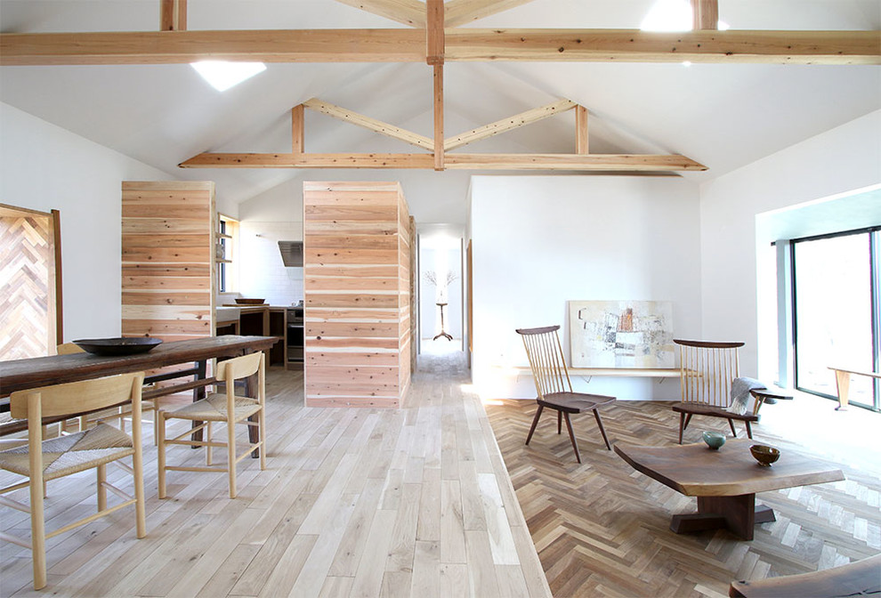 Immagine di un soggiorno stile rurale aperto con pareti bianche, parquet chiaro, stufa a legna, cornice del camino in cemento, TV a parete e pavimento bianco