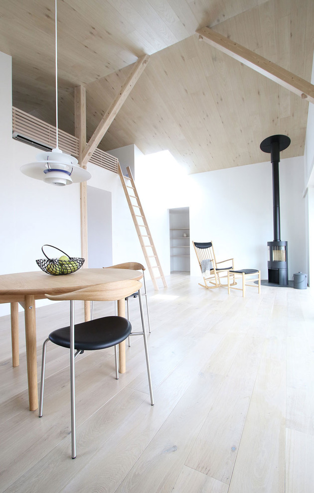 Cette photo montre un salon mansardé ou avec mezzanine scandinave avec un mur blanc, parquet clair, une cheminée d'angle, un manteau de cheminée en bois, un téléviseur fixé au mur et un sol blanc.