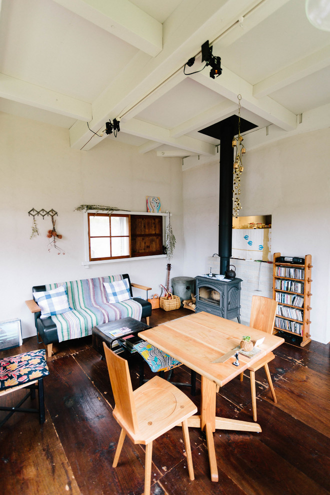 Aménagement d'un petit salon scandinave ouvert avec un mur gris, parquet foncé, un poêle à bois et aucun téléviseur.