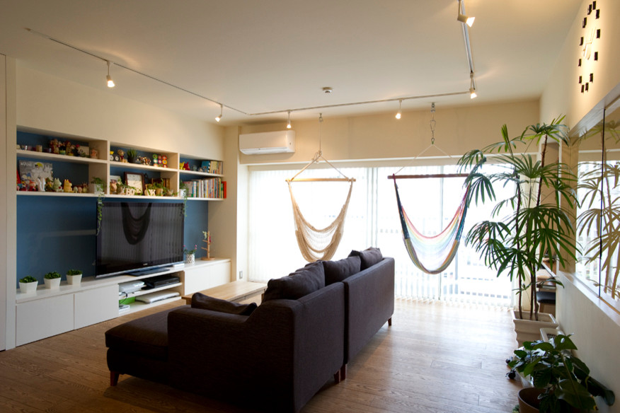 Foto de salón para visitas abierto minimalista de tamaño medio sin chimenea con paredes blancas, suelo de madera en tonos medios y pared multimedia