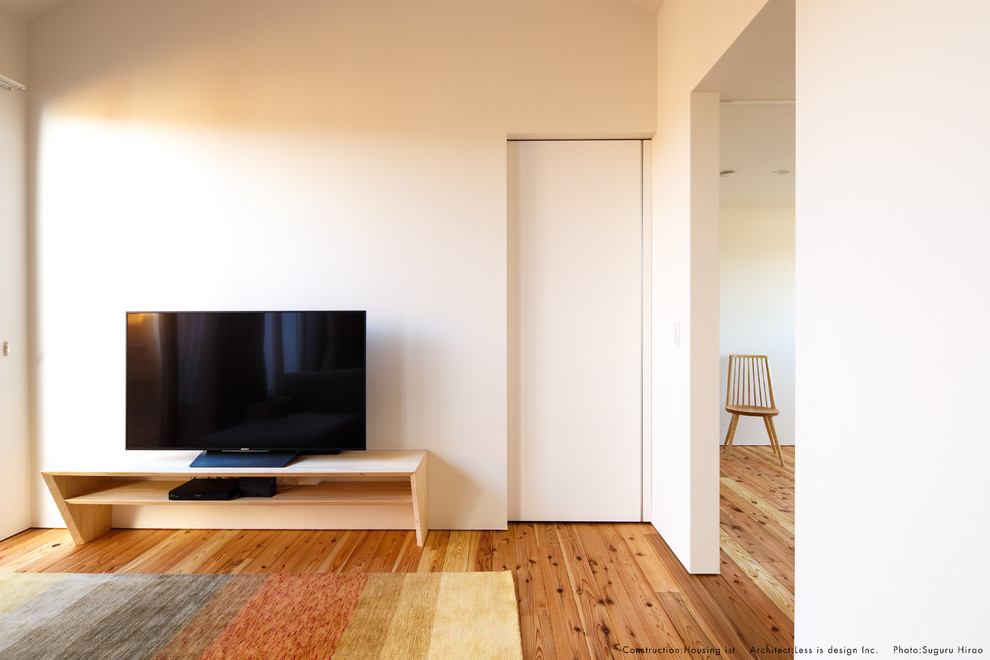 Bild på ett mellanstort allrum med öppen planlösning, med vita väggar, mellanmörkt trägolv, en fristående TV och beiget golv