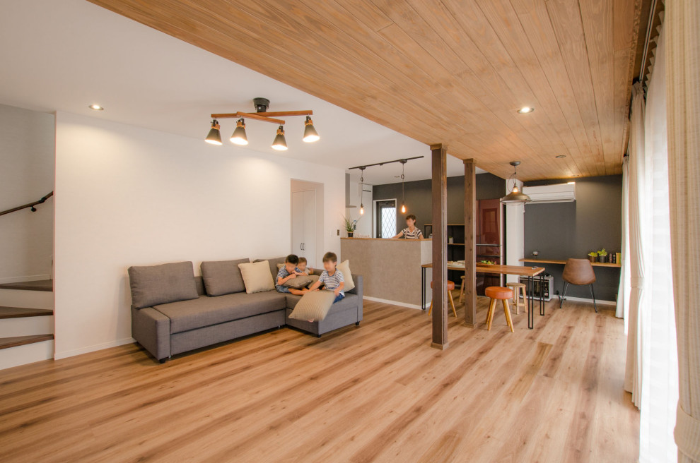 На фото: открытая гостиная комната среднего размера в стиле лофт с разноцветными стенами, паркетным полом среднего тона, коричневым полом, деревянным потолком и обоями на стенах без камина