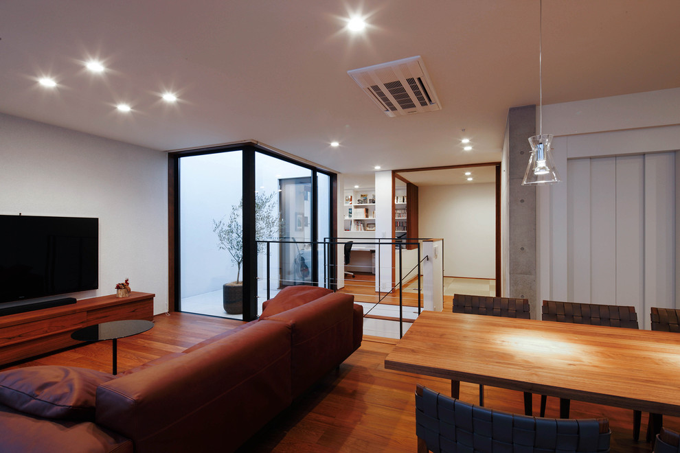 Großes, Offenes Modernes Wohnzimmer mit bunten Wänden, dunklem Holzboden, braunem Boden und freistehendem TV in Tokio