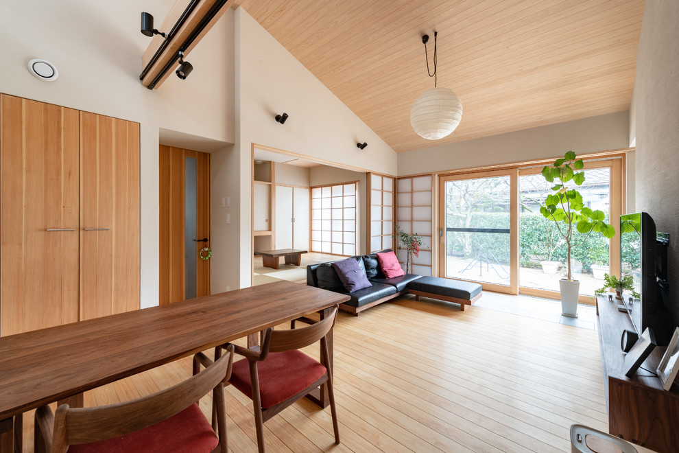 Exempel på ett asiatiskt vardagsrum, med vita väggar, ljust trägolv, en fristående TV och brunt golv