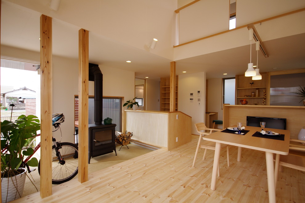 東京23区にある中くらいな北欧スタイルのおしゃれなLDK (白い壁、淡色無垢フローリング、標準型暖炉、据え置き型テレビ、木材の暖炉まわり、ベージュの床) の写真