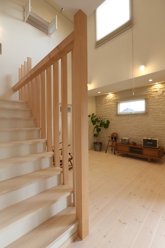 Foto på ett minimalistiskt allrum med öppen planlösning, med vita väggar, ljust trägolv, en fristående TV och vitt golv