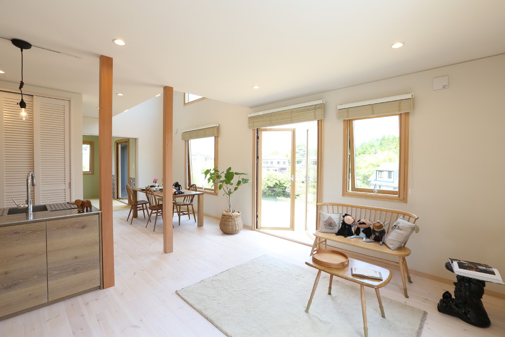 Offenes Skandinavisches Wohnzimmer mit TV-Wand, weißer Wandfarbe, hellem Holzboden und beigem Boden in Sonstige