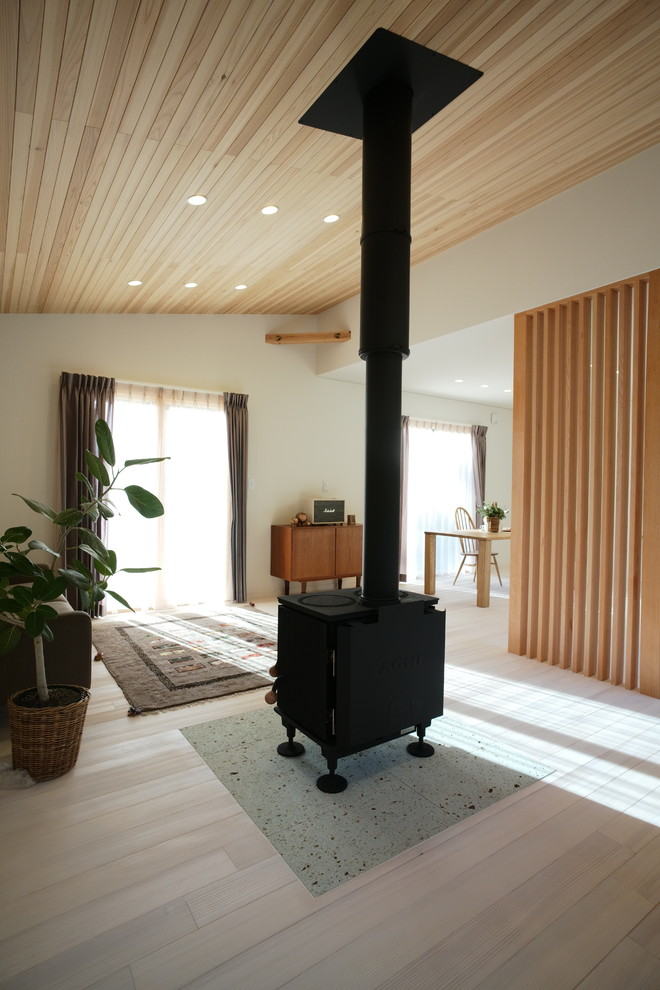 Idee per un soggiorno moderno aperto con pareti bianche, parquet chiaro, stufa a legna, cornice del camino in pietra, TV autoportante e pavimento bianco