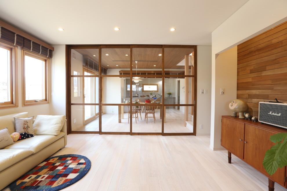 Bild på ett minimalistiskt allrum med öppen planlösning, med vita väggar, ljust trägolv och en fristående TV