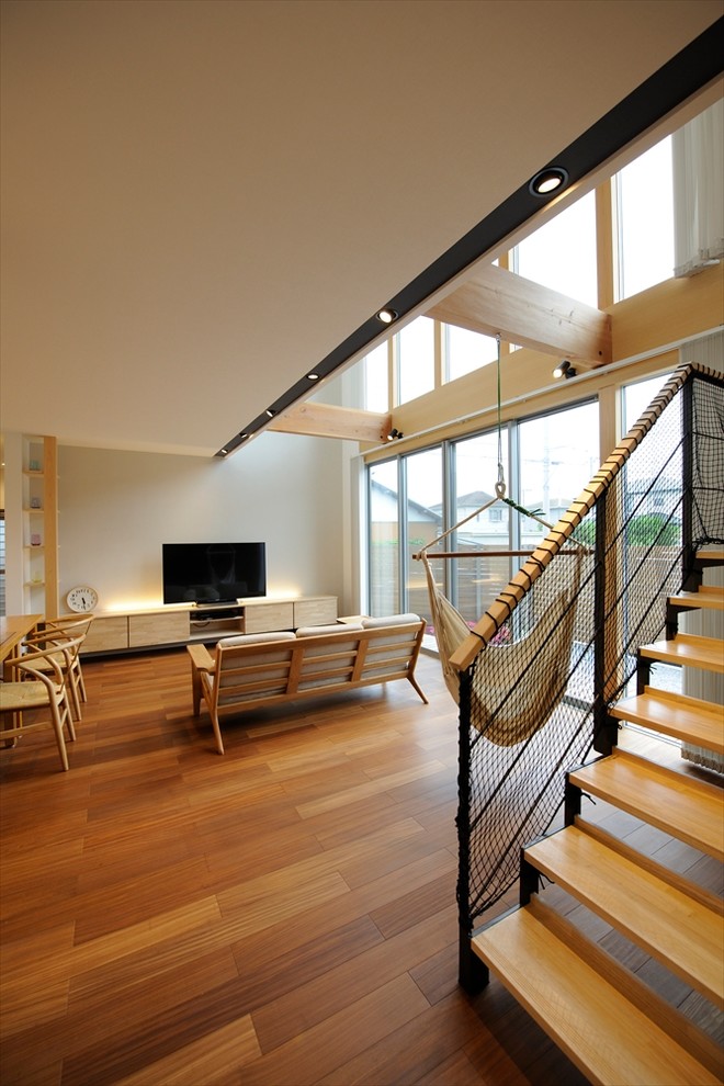 Стильный дизайн: открытая гостиная комната среднего размера в стиле модернизм с белыми стенами, темным паркетным полом, телевизором на стене и коричневым полом - последний тренд