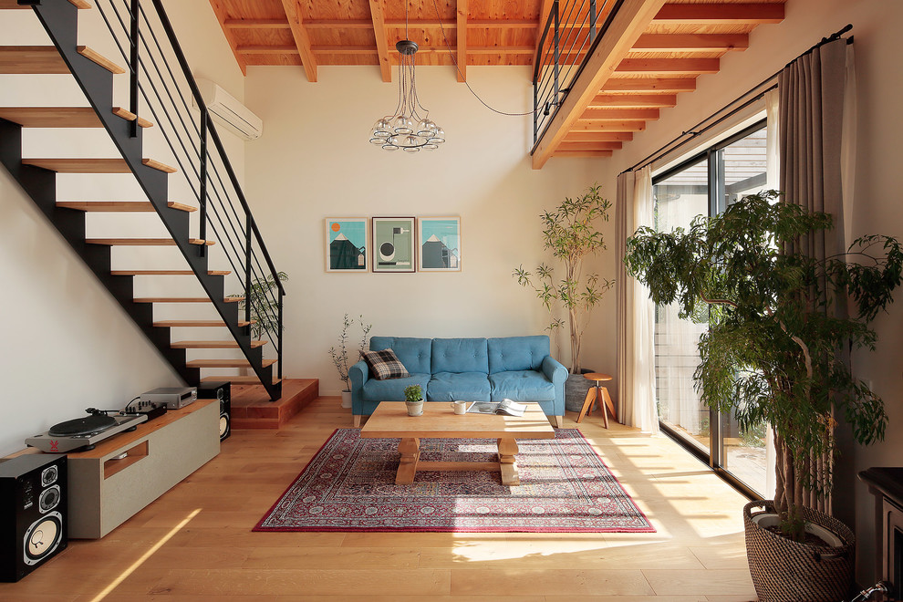 Offenes Asiatisches Wohnzimmer mit weißer Wandfarbe, hellem Holzboden, Kaminofen und beigem Boden in Sonstige