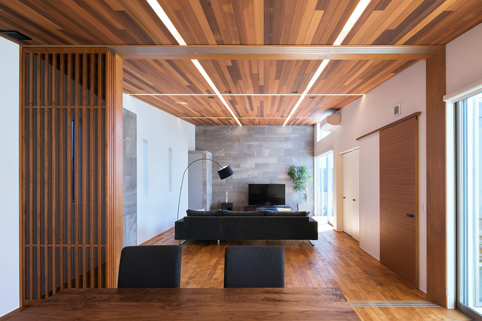 Ispirazione per un soggiorno minimalista aperto con pareti bianche, pavimento in legno massello medio, TV autoportante e pavimento marrone