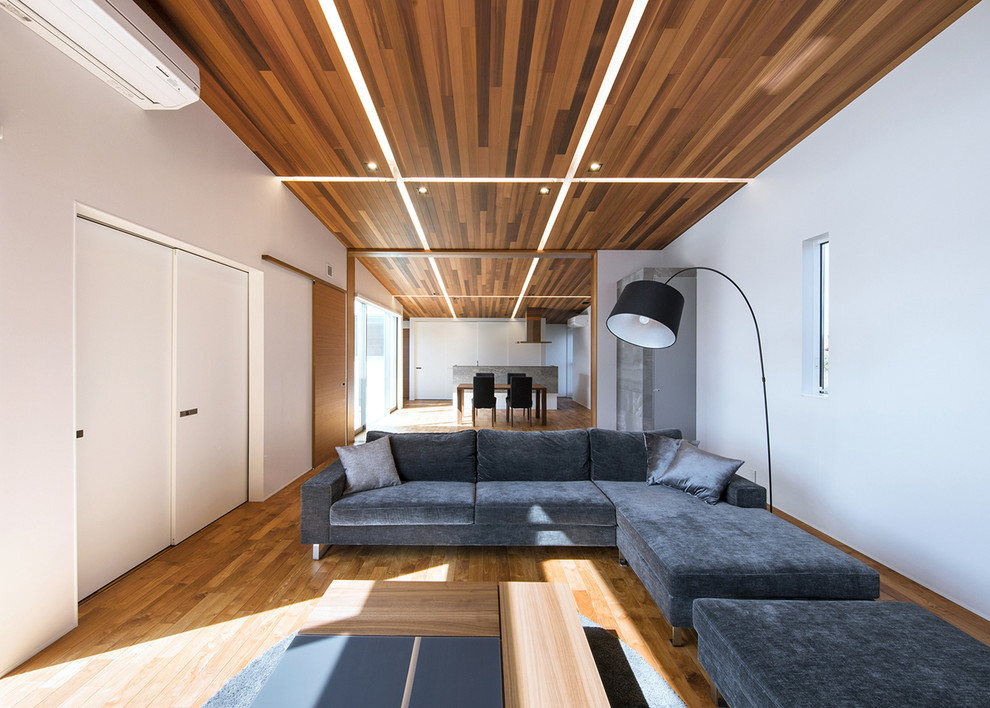 Aménagement d'un salon moderne ouvert avec un mur blanc, un sol en bois brun, un téléviseur indépendant et un sol marron.