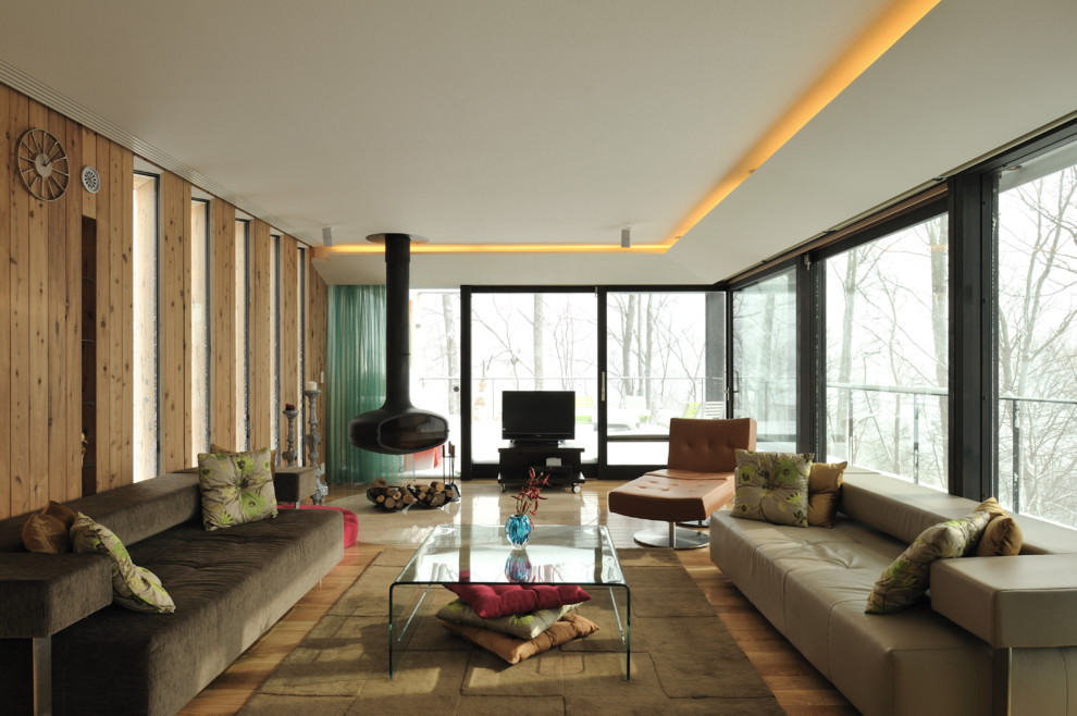 Exemple d'un salon tendance avec un mur marron, un sol en bois brun, cheminée suspendue, un manteau de cheminée en carrelage et un téléviseur indépendant.