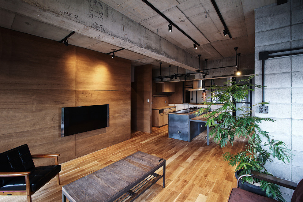 Exempel på ett industriellt allrum med öppen planlösning, med flerfärgade väggar, mellanmörkt trägolv, en väggmonterad TV och brunt golv
