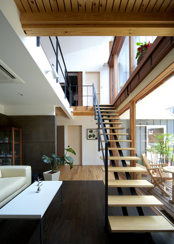 Стильный дизайн: гостиная комната в современном стиле с белыми стенами, светлым паркетным полом и коричневым полом без камина - последний тренд