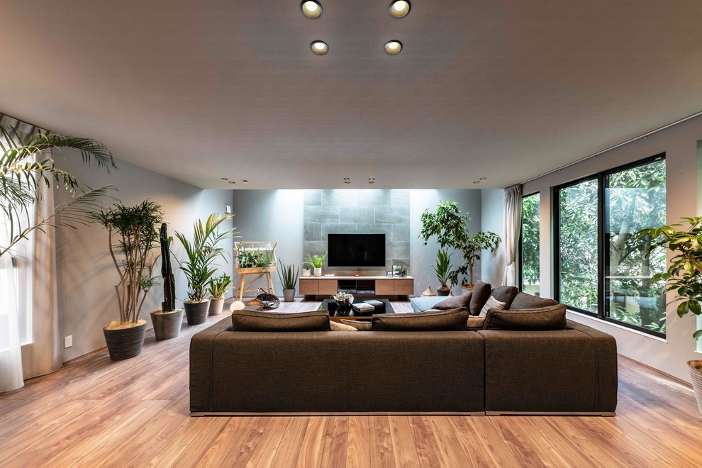Idéer för ett mellanstort modernt allrum med öppen planlösning, med en hemmabar, plywoodgolv, en väggmonterad TV, brunt golv och grå väggar