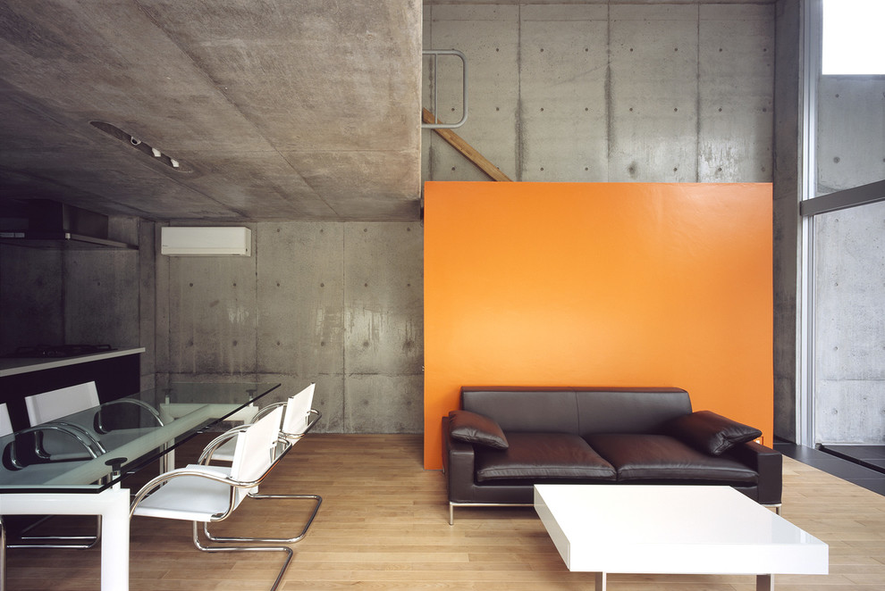 Urban open plan living room feature wall in Tokyo with grey walls, light hardwood flooring, no fireplace and no tv.
