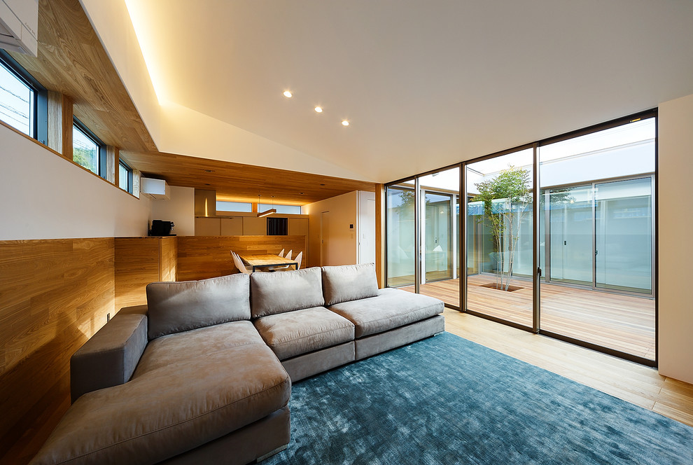 Идея дизайна: парадная, открытая гостиная комната среднего размера в стиле модернизм с белыми стенами, телевизором на стене, коричневым полом и полом из фанеры без камина