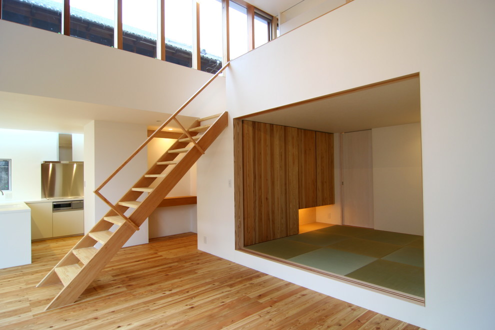 Fernseherloses, Offenes Asiatisches Wohnzimmer ohne Kamin mit weißer Wandfarbe und hellem Holzboden in Osaka
