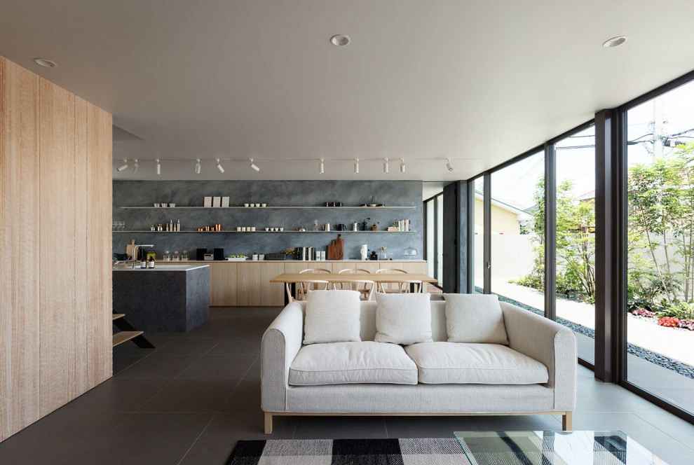 Cette image montre un salon minimaliste ouvert avec un mur gris, un sol en carrelage de porcelaine, un téléviseur fixé au mur, un sol gris et une salle de réception.