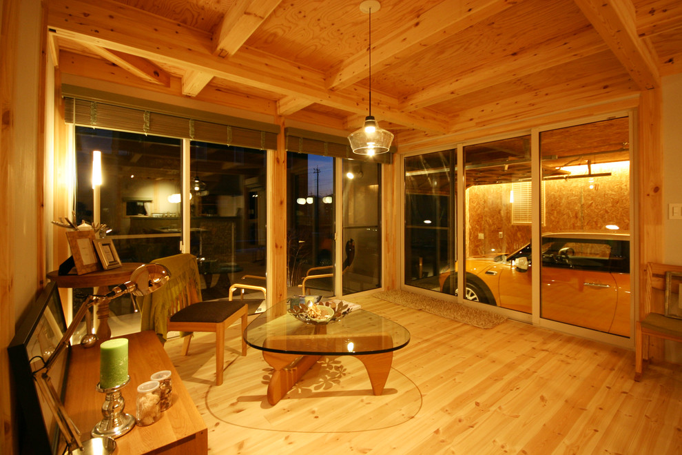 Modernes Wohnzimmer mit weißer Wandfarbe, hellem Holzboden und freistehendem TV in Sonstige