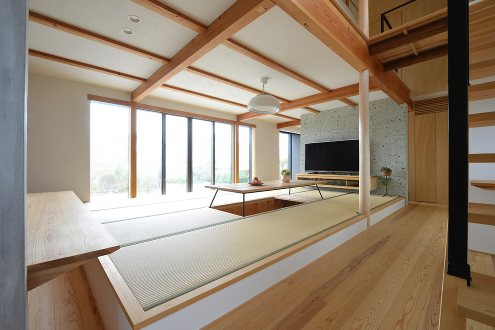 Offenes Asiatisches Wohnzimmer mit weißer Wandfarbe, Tatami-Boden, freistehendem TV und grünem Boden in Sonstige
