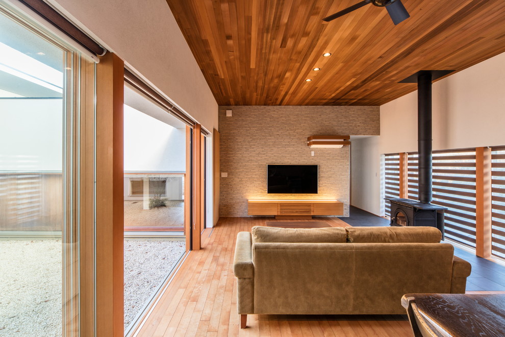 Foto de salón abierto de estilo zen con paredes blancas, suelo de madera clara y televisor colgado en la pared