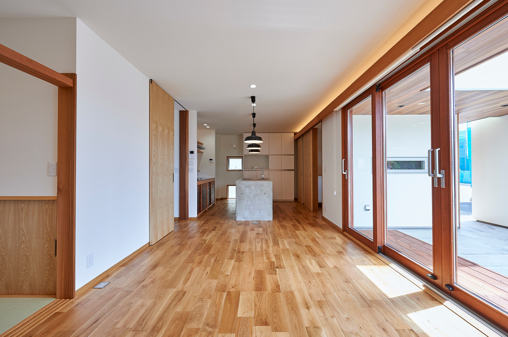 Foto de salón abierto actual sin chimenea con paredes blancas y suelo de madera en tonos medios
