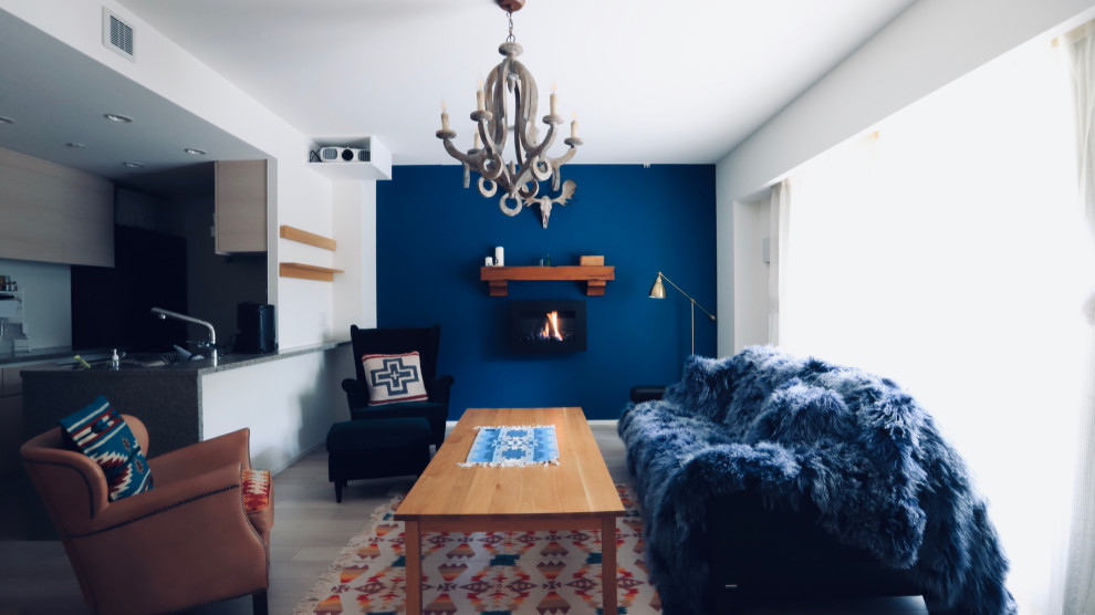 Modelo de salón abierto de estilo americano de tamaño medio sin televisor con paredes azules, suelo de contrachapado, chimeneas suspendidas, marco de chimenea de madera y suelo gris