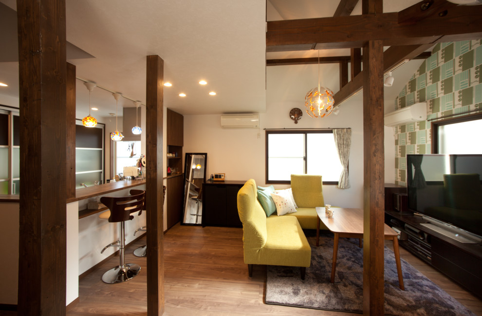 Cette photo montre un petit salon nature ouvert avec un mur blanc, un sol en bois brun et un sol marron.