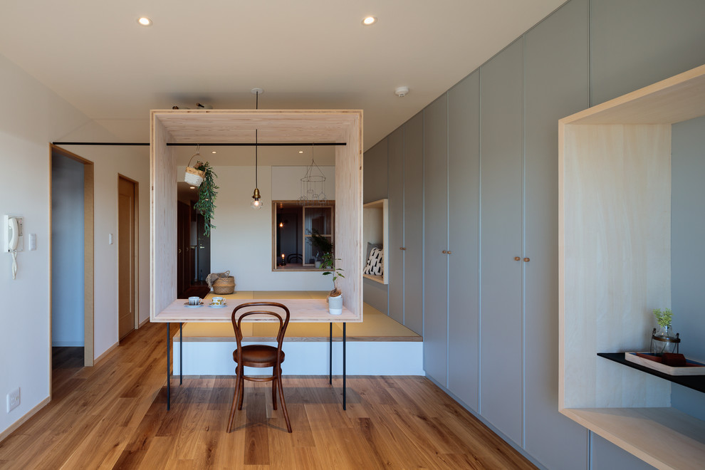 Inspiration pour un petit salon design ouvert avec un mur gris, un sol en contreplaqué et un sol marron.