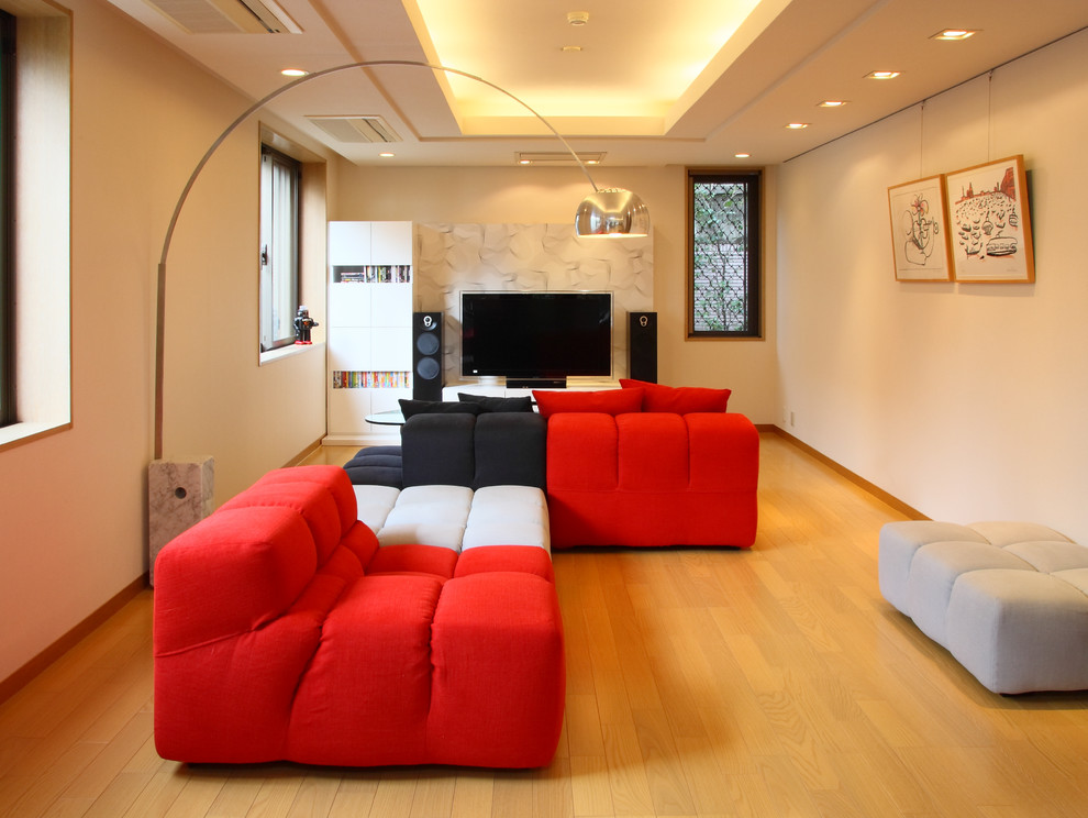 Modelo de salón actual sin chimenea con paredes blancas, suelo de madera clara y televisor independiente