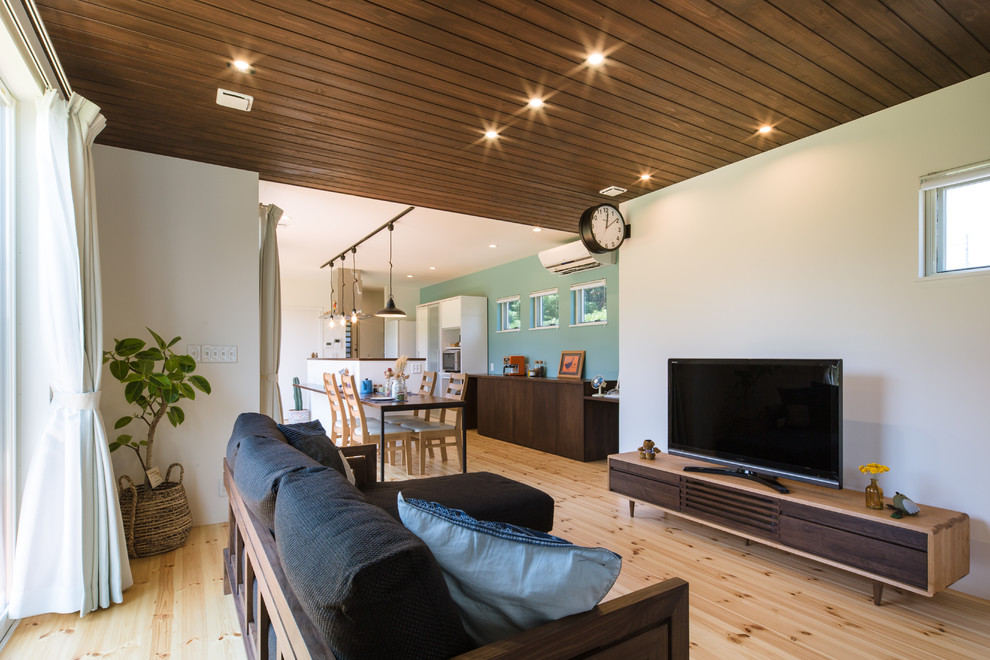 Immagine di un soggiorno etnico aperto con pareti bianche, parquet chiaro, TV autoportante e pavimento beige