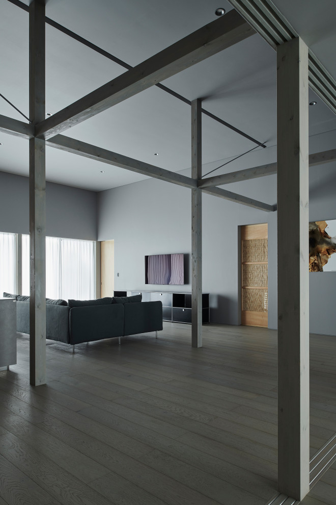 Стильный дизайн: большая парадная, открытая гостиная комната в стиле модернизм с серыми стенами, деревянным полом, телевизором на стене, серым полом, потолком с обоями и обоями на стенах без камина - последний тренд