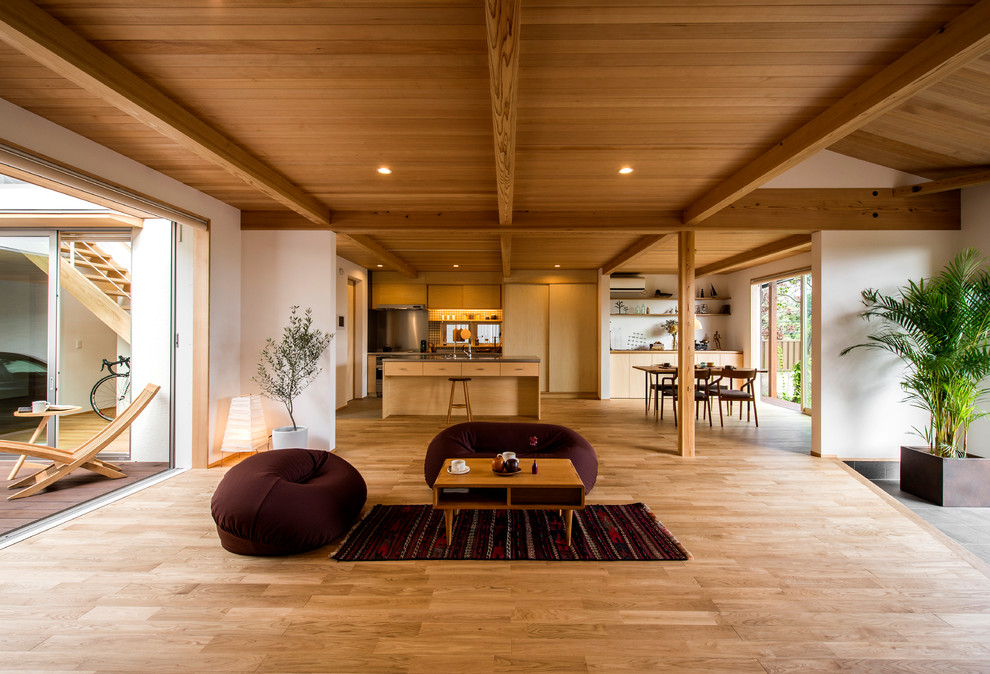 Modelo de salón abierto de estilo zen con paredes blancas, suelo de madera clara y suelo beige