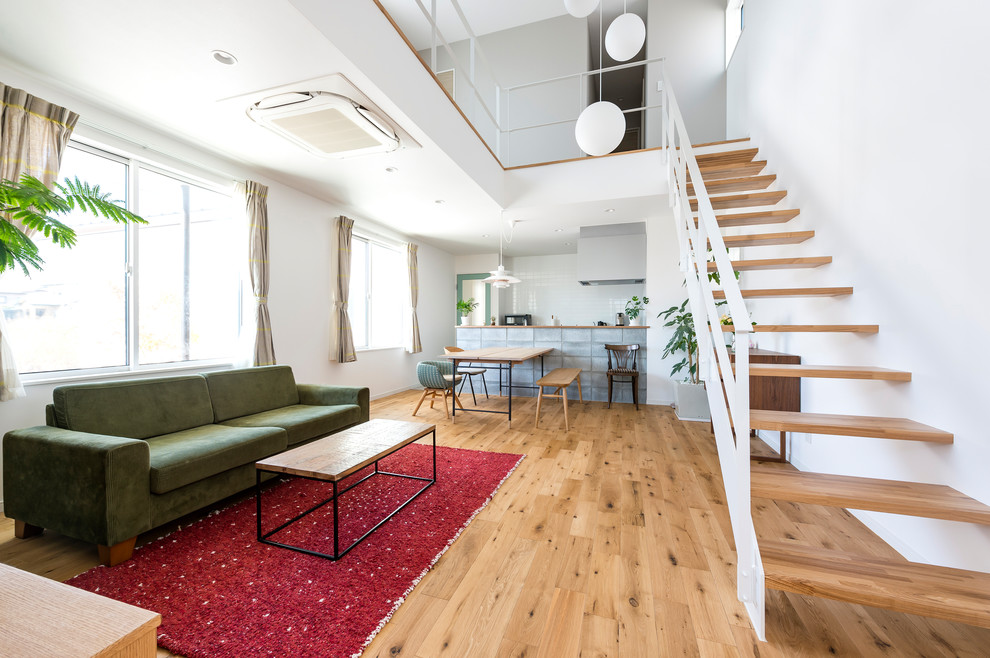 Cette image montre un salon nordique ouvert avec un mur blanc, un sol en bois brun et un sol marron.