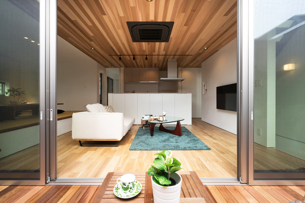 Modelo de salón abierto de estilo zen con paredes blancas, suelo de madera en tonos medios y suelo marrón