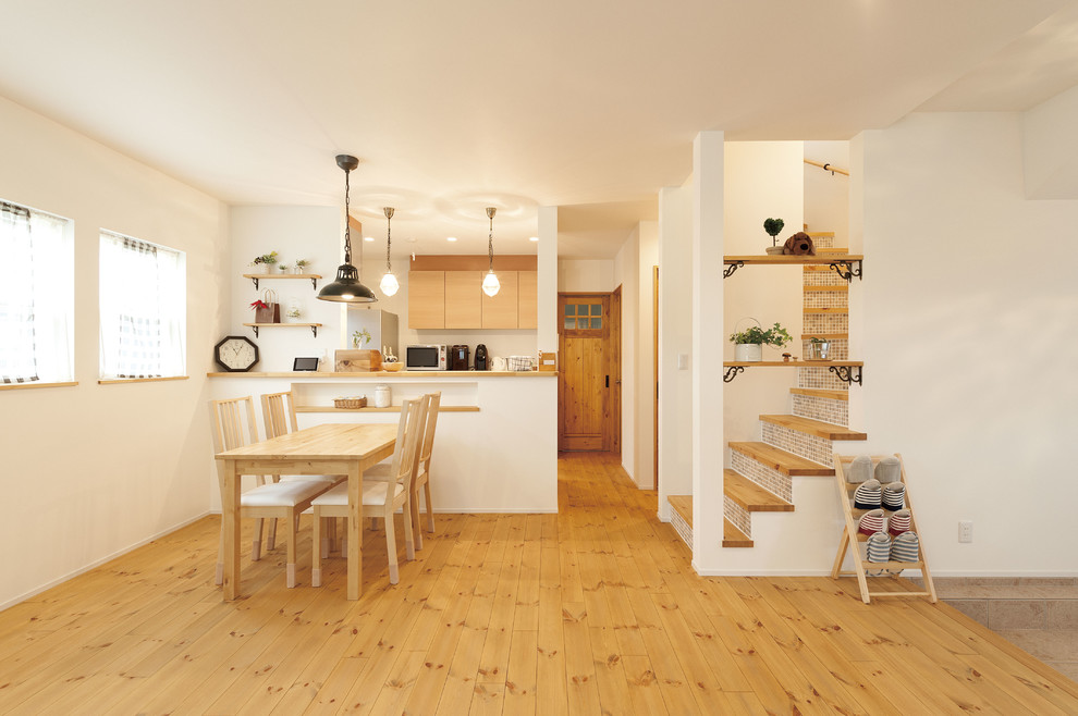Offenes Asiatisches Wohnzimmer mit weißer Wandfarbe, braunem Holzboden und braunem Boden in Osaka