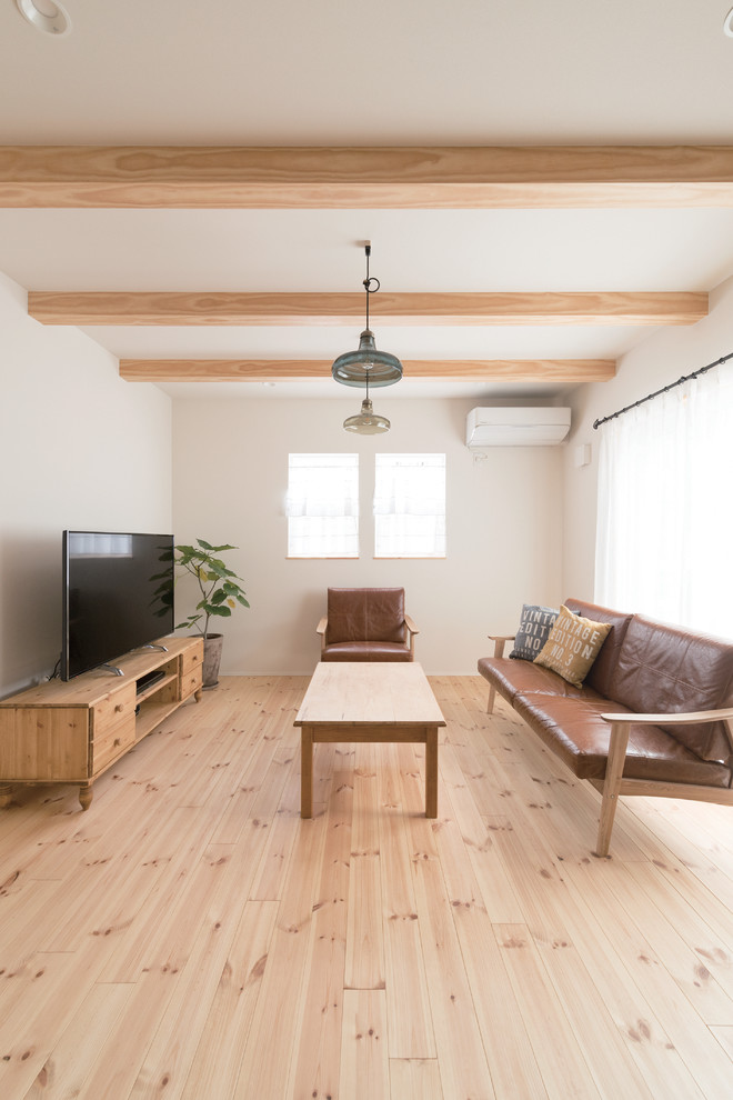This is an example of a world-inspired open plan living room in Osaka with white walls, medium hardwood flooring, a freestanding tv and brown floors.