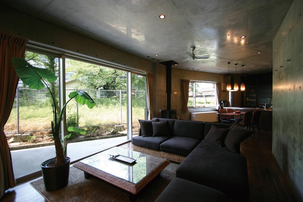 Diseño de salón abierto de estilo zen con paredes grises, estufa de leña y marco de chimenea de hormigón