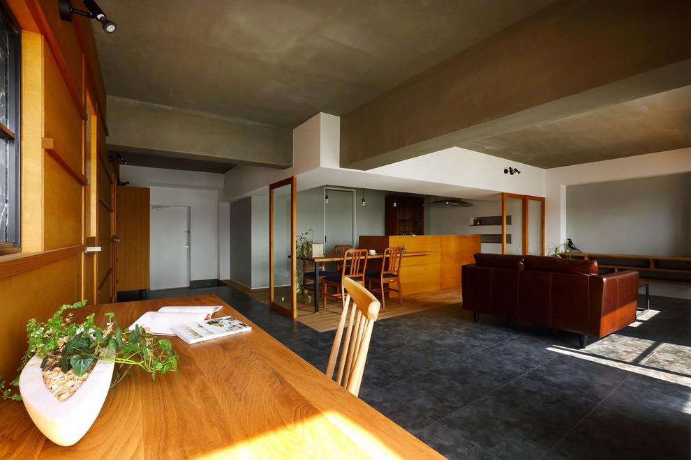 На фото: открытая гостиная комната среднего размера в стиле ретро с белыми стенами, полом из керамической плитки, телевизором на стене и серым полом