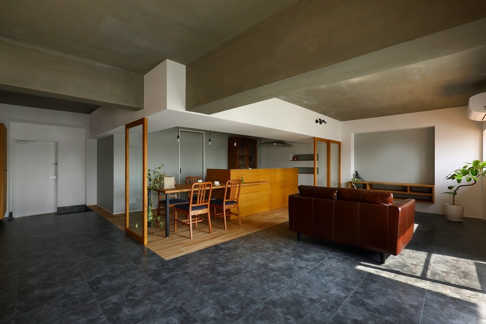 Modelo de salón abierto asiático de tamaño medio con paredes blancas, suelo de baldosas de cerámica, televisor colgado en la pared y suelo gris